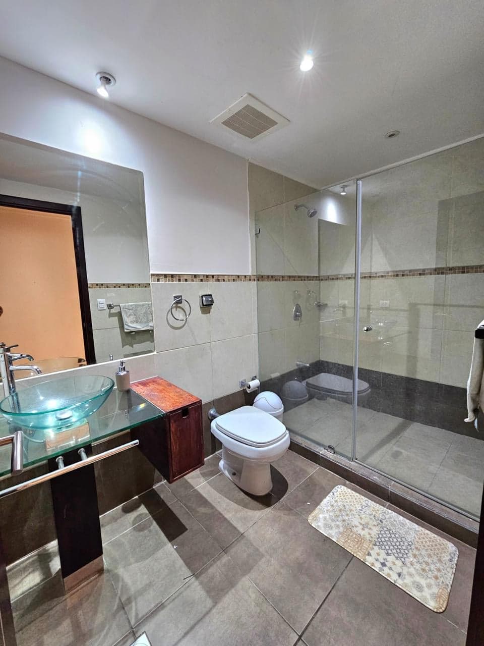 Baño con lavatorio de vidrio y ducha