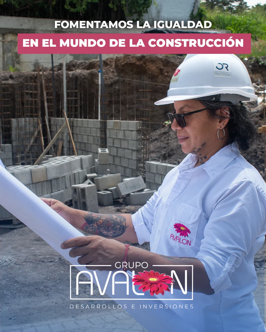 «Fomentamos la igualdad en el mundo de la construcción». Una integrante del equipo, con casco de Oeste Realty y camisa de Avalon, revisa un plano junto a muros de bloques en construcción.