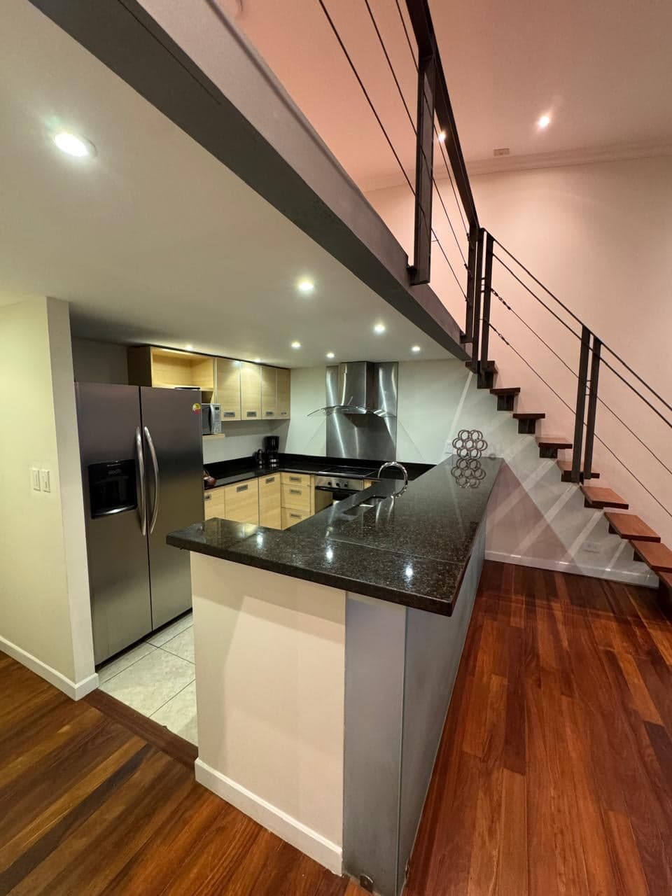 Cocina con refrigeradora de acero inoxidable y escalera al mezzanine